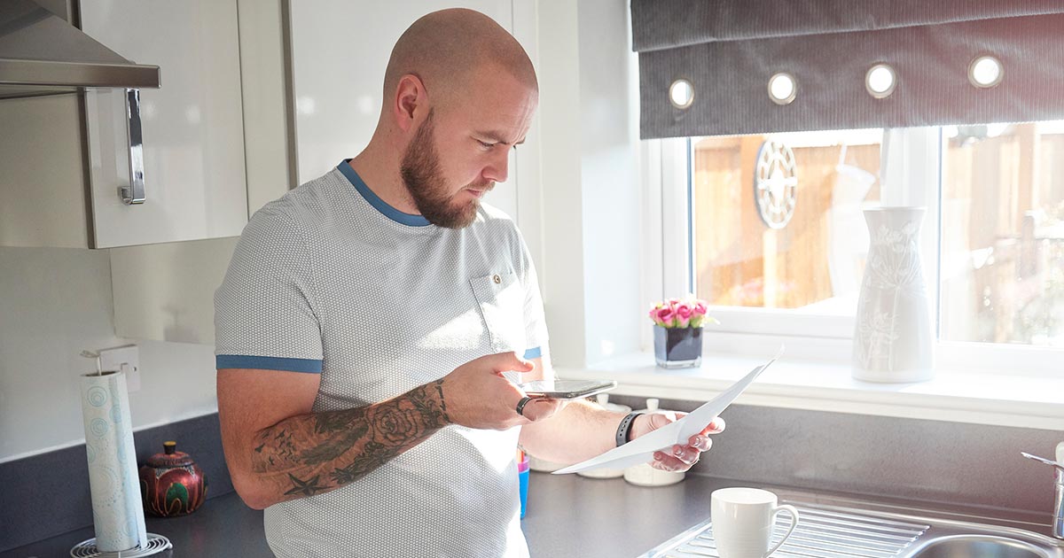 man reviewing mortgage statement kitchen