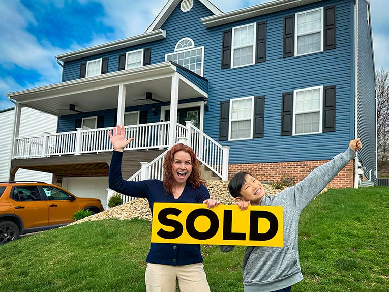mom and son holding sold sign