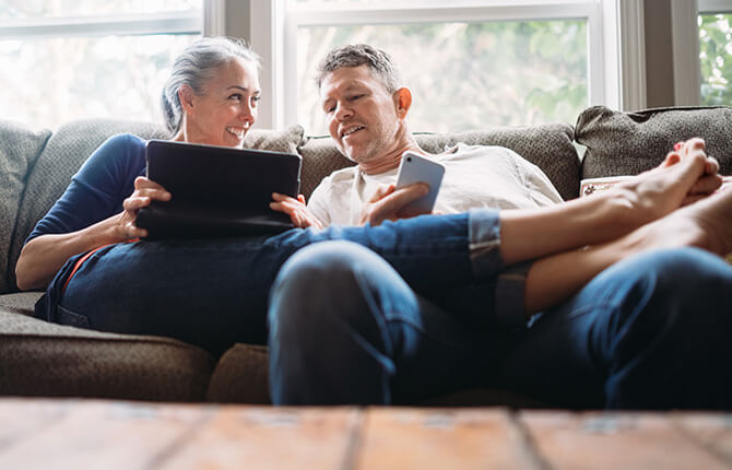 Couple relaxing on couch with tablet in hand